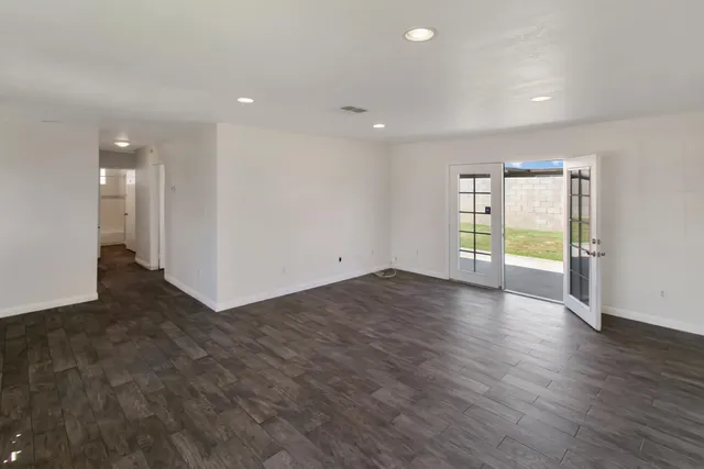 an empty room with wooden floor and natural light
