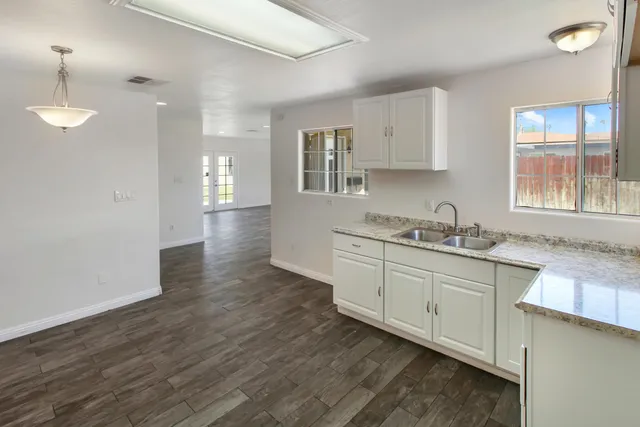 a kitchen with granite countertop a sink cabinets and wooden floor