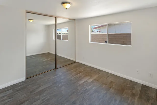 an empty room with wooden floor and mirror