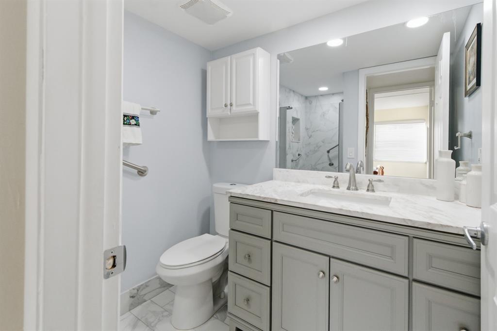 820 Flanders South, Unit 280 Delray Beach, FL 33484 - Photo 11 of 16 a bathroom with a granite countertop sink a toilet and a mirror