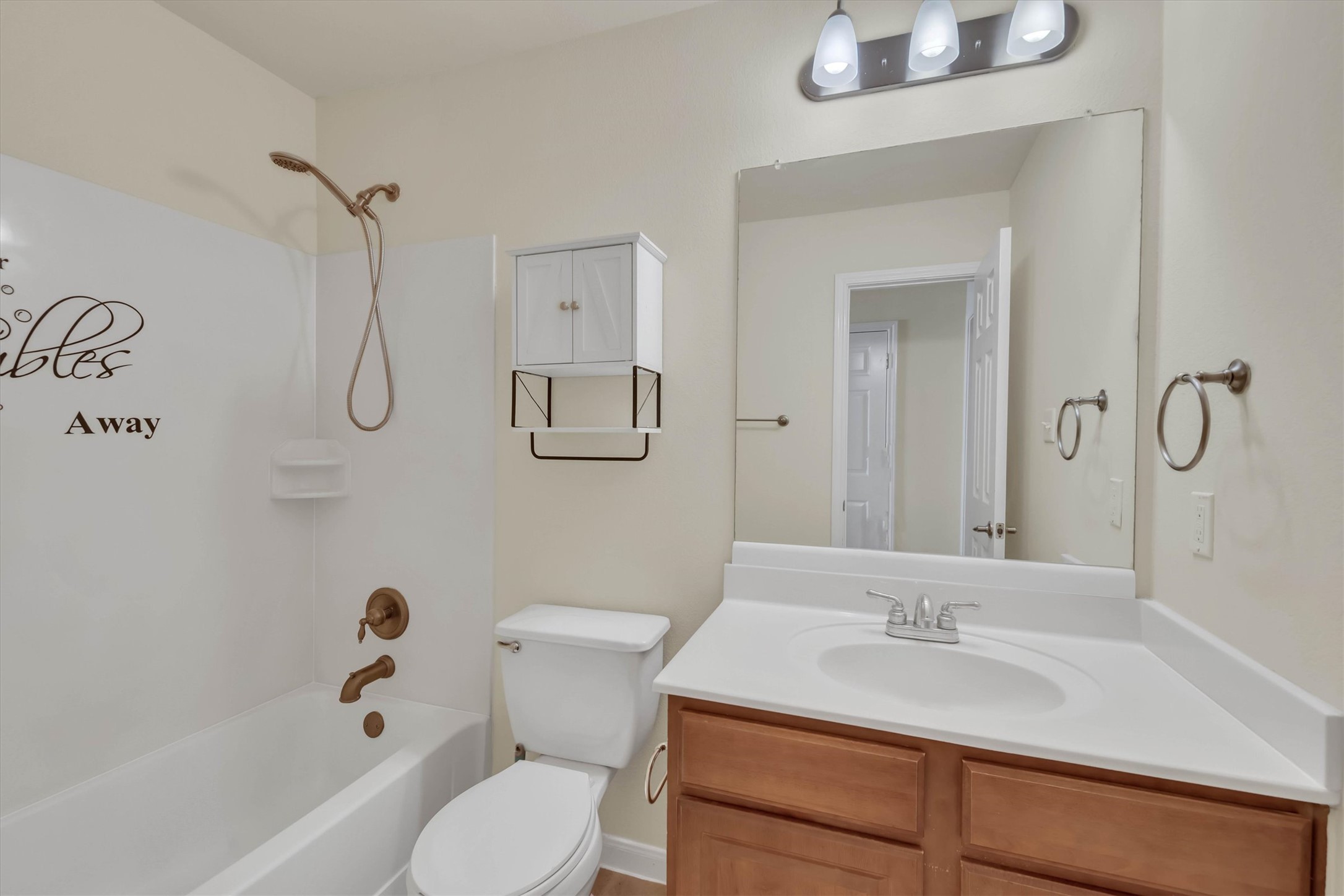 18420 Masi Loop Pflugerville, TX 78660 - Photo 26 of 33 Bathroom featuring a white tub-shower combination with bronze fixtures, a white toilet, and a vanity with wood-finish cabinetry and a white countertop