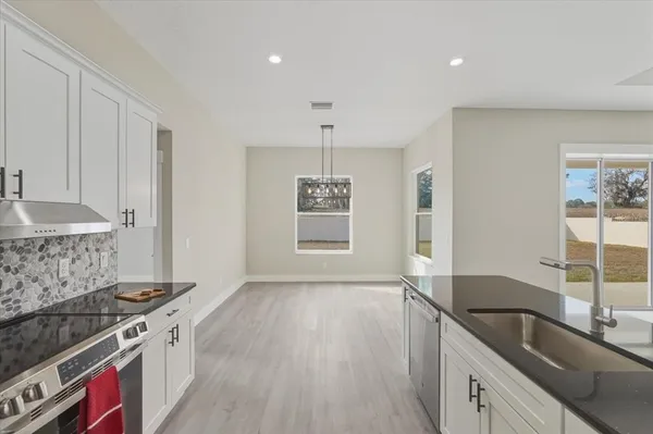 a kitchen with stainless steel appliances a stove top oven a sink a refrigerator and white cabinets