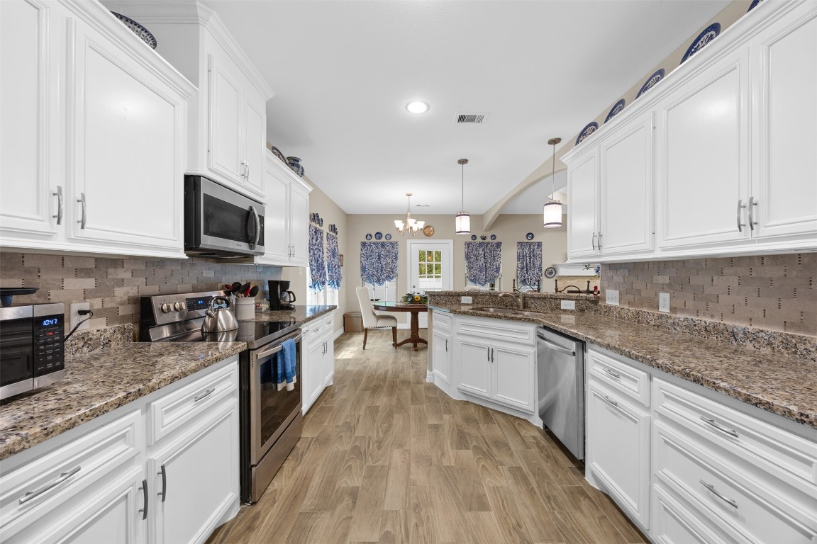 42 Trail Lake Trinity, TX 75862 - Photo 13 of 50 a large kitchen with stainless steel appliances granite countertop a stove top oven a sink dishwasher and white cabinets with wooden floor