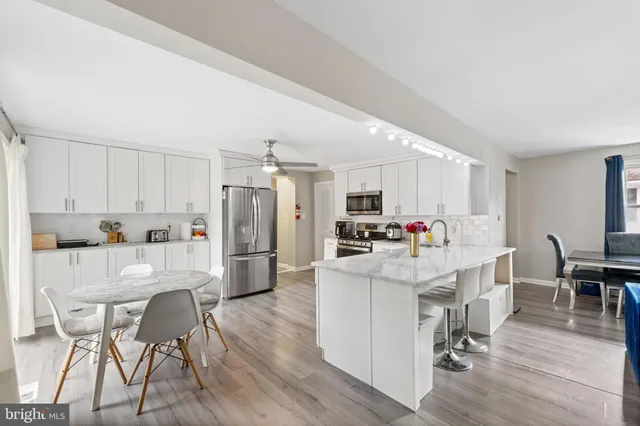 a kitchen with stainless steel appliances a dining table chairs stove and white cabinets
