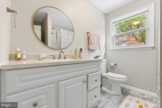 a bathroom with a granite countertop toilet a sink and a mirror