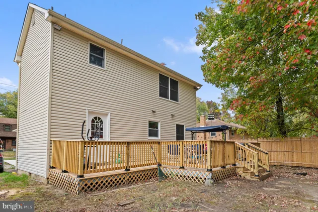 a view of a white house with large windows and wooden fence