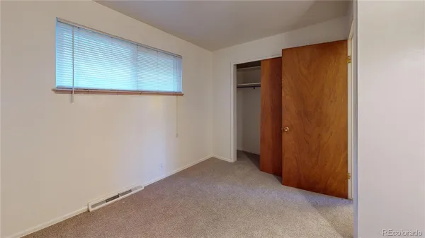 a view of an empty room with closet and a window