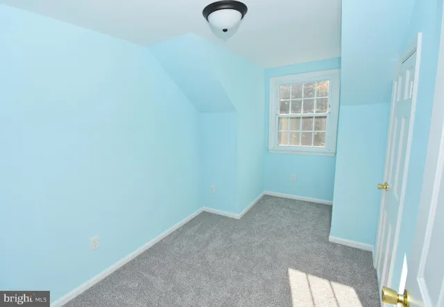 an empty room with a chandelier fan and windows