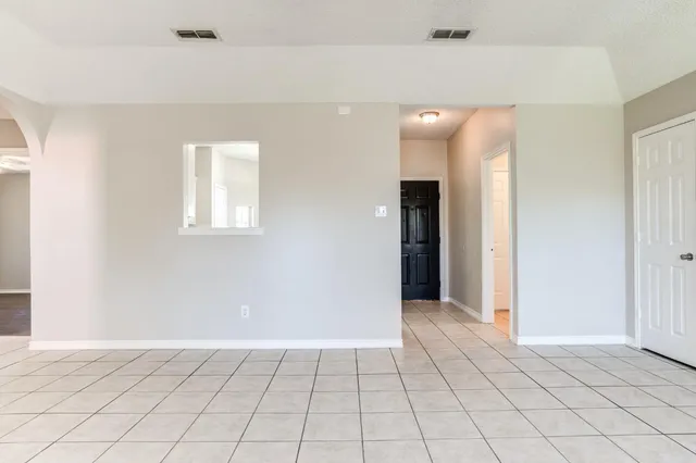 a view of an empty room with window and chandelier fan