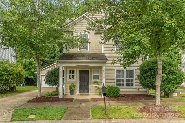 a front view of a house with a yard and potted plants