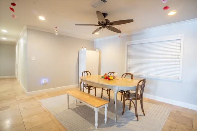 a dining room with furniture and a chandelier fan