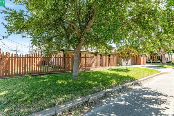 a view of a backyard with large trees and wooden fence