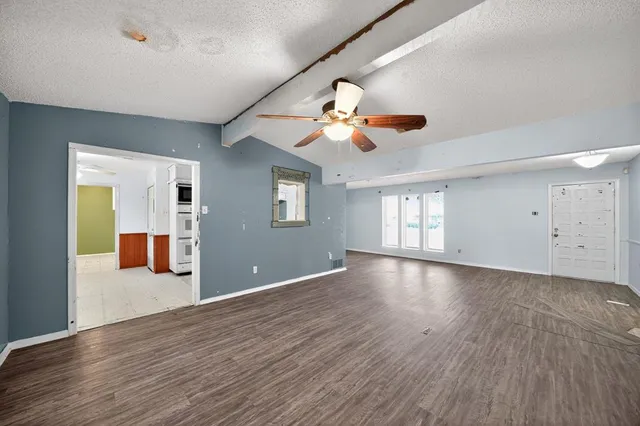 a view of an empty room with window and wooden floor