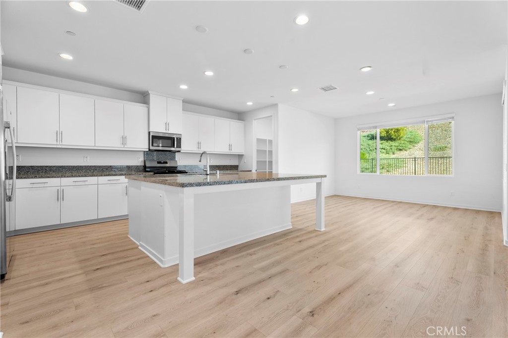 18121 Outlook Way Saugus, CA 91350 - Photo 8 of 59 a large kitchen with stainless steel appliances granite countertop a stove a sink a refrigerator white cabinets with wooden floor