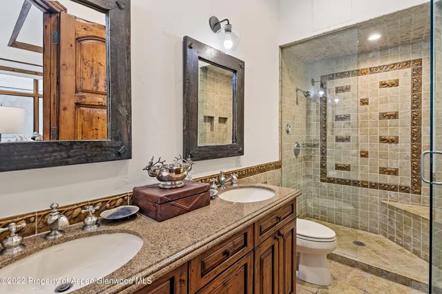 a bathroom with a granite countertop sink a toilet a mirror and shower