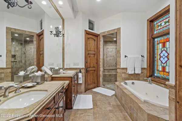a bathroom with a granite countertop tub sink a mirror and a bathtub