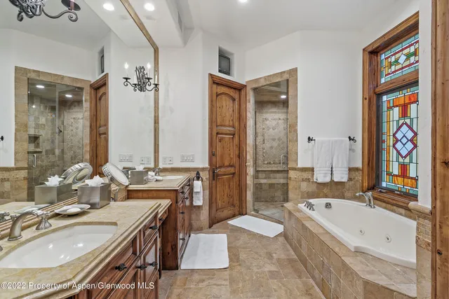 a bathroom with a granite countertop tub sink a mirror and a bathtub