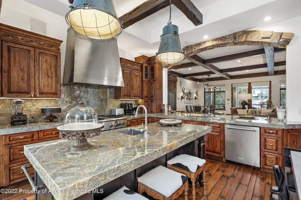a kitchen with stainless steel appliances granite countertop a sink a stove and chairs