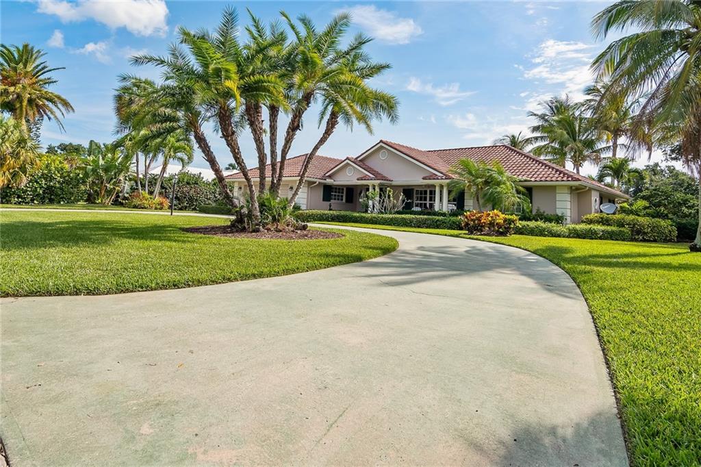 1626 Indian Bay Drive Vero Beach, FL 32963 - Photo 3 of 35 a view of a white house with a big yard and palm trees