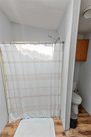 a large kitchen with stainless steel appliances a stove a sink dishwasher a refrigerator white cabinets wooden floor and a dining table