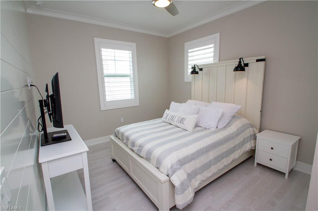 251 Indies Drive East, Unit 202 Naples, FL 34114 - Photo 15 of 48 a bedroom with a bed and a flat tv screen on the dresser