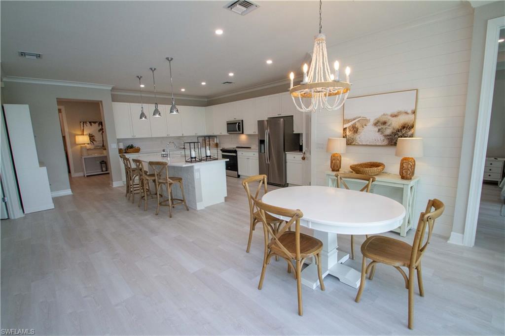 251 Indies Drive East, Unit 202 Naples, FL 34114 - Photo 16 of 48 a view of a dining room with furniture and chandelier