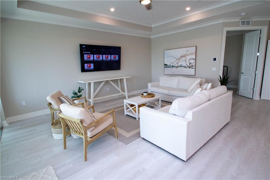 251 Indies Drive East, Unit 202 Naples, FL 34114 - Photo 17 of 48 a living room with furniture and a flat screen tv