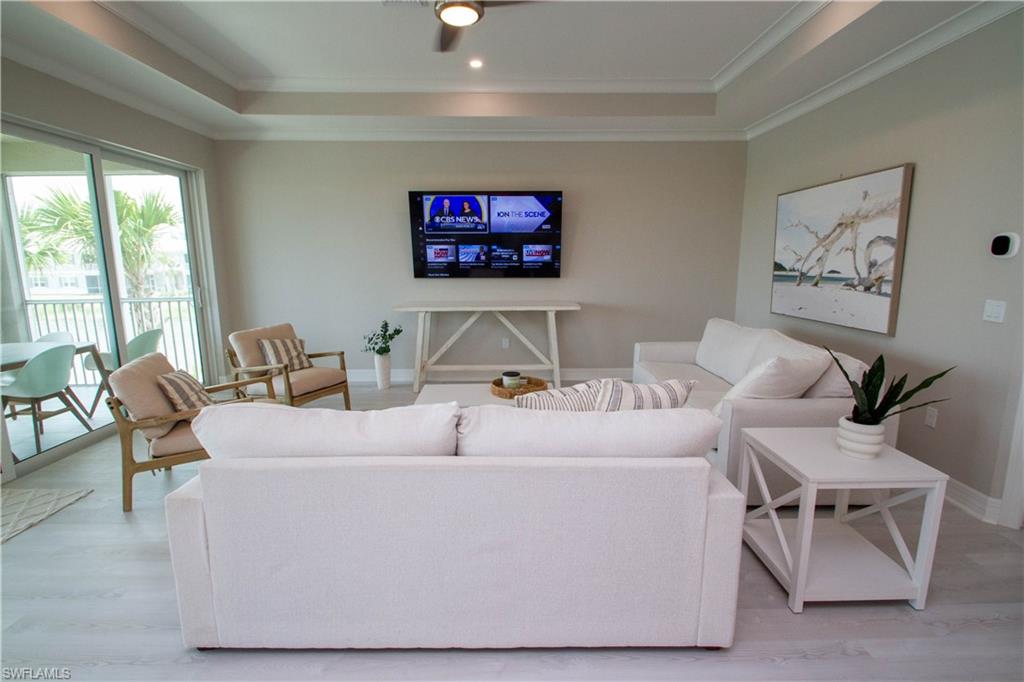 251 Indies Drive East, Unit 202 Naples, FL 34114 - Photo 20 of 48 a living room with furniture and a flat screen tv