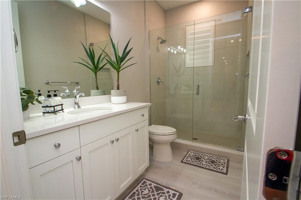 251 Indies Drive East, Unit 202 Naples, FL 34114 - Photo 23 of 48 a bathroom with a granite countertop sink a toilet and shower