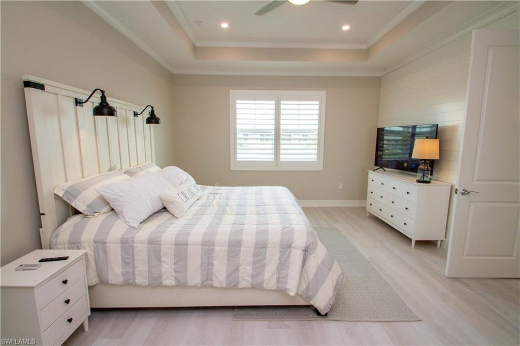 251 Indies Drive East, Unit 202 Naples, FL 34114 - Photo 32 of 48 a bedroom with a bed and a tv on the dresser