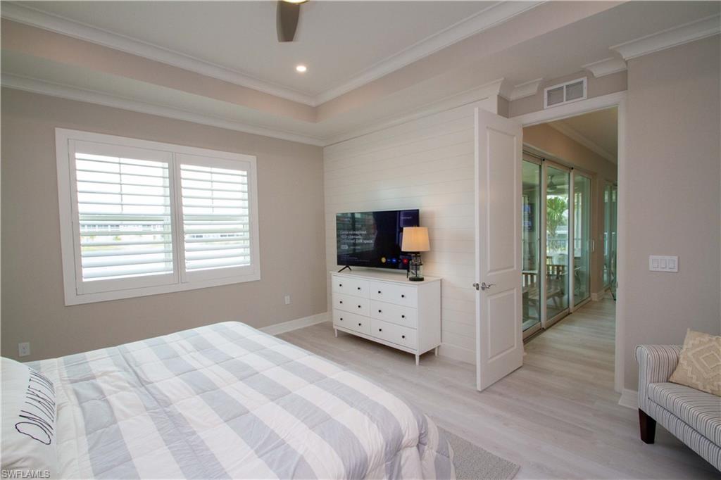251 Indies Drive East, Unit 202 Naples, FL 34114 - Photo 33 of 48 a bedroom with a bed and a flat screen tv