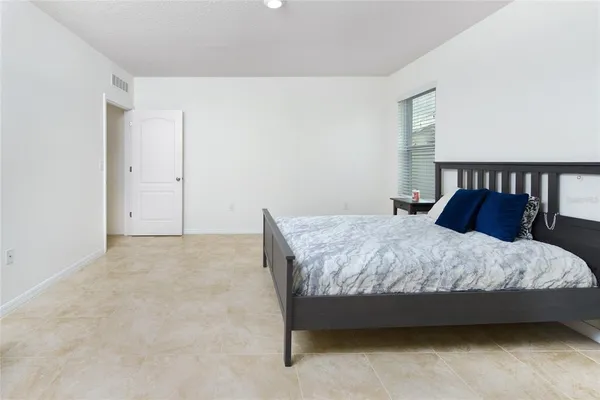 a spacious bedroom with a bed and cabinet