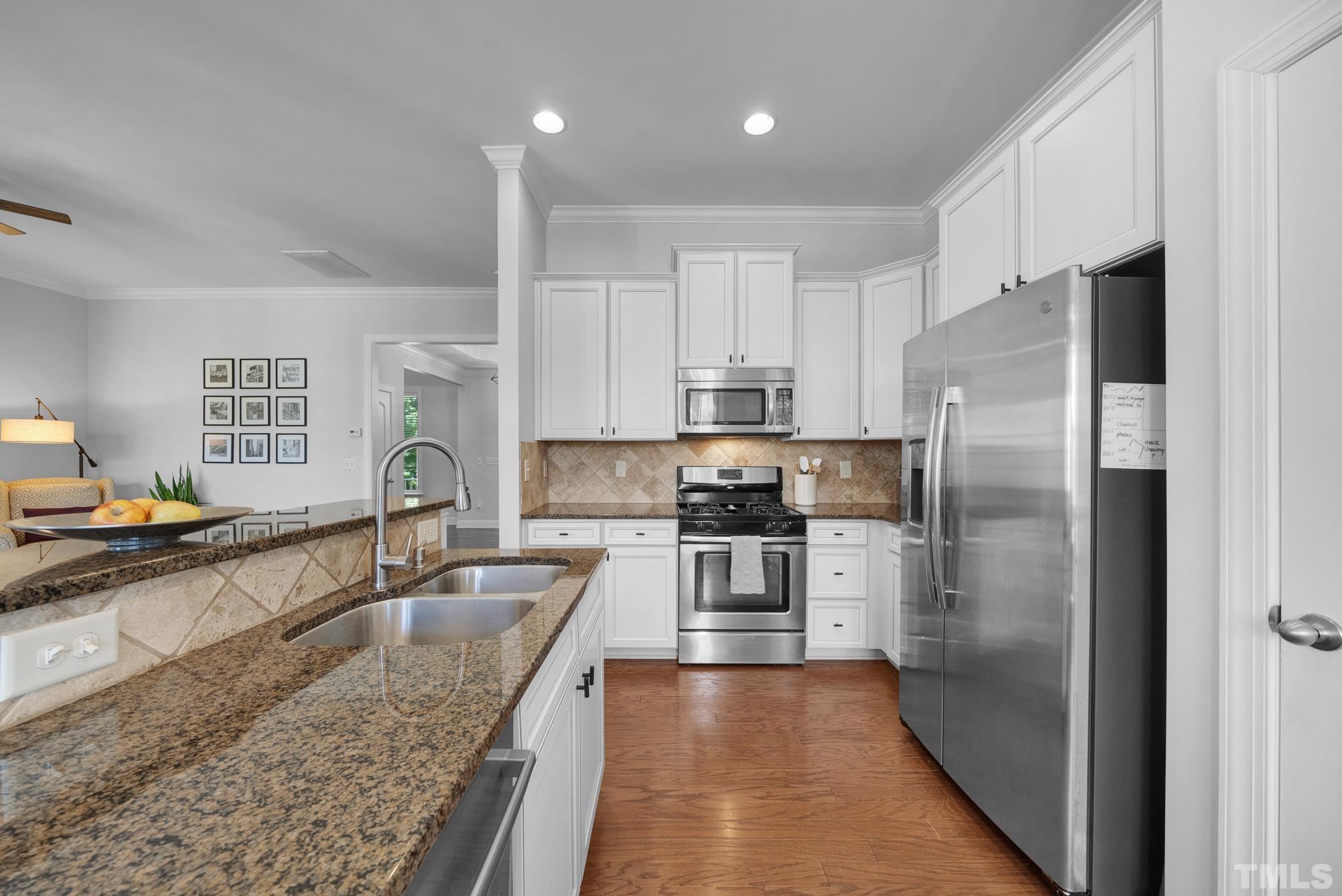 907 Chapanoke Road Raleigh, NC 27603 - Photo 9 of 26 a kitchen with stainless steel appliances granite countertop a refrigerator a stove and a sink with wooden floors