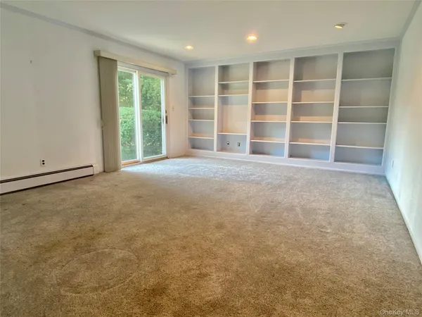an empty room with a large window and cabinet