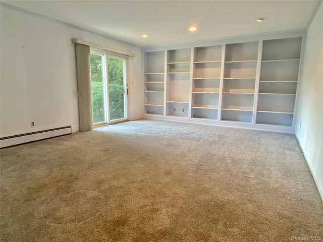 an empty room with a large window and cabinet
