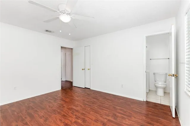 an empty room with wooden floor and a ceiling fan