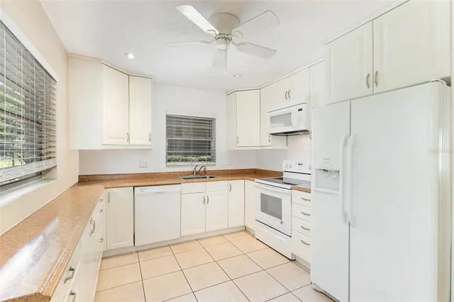 a kitchen with granite countertop white cabinets white appliances sink and window