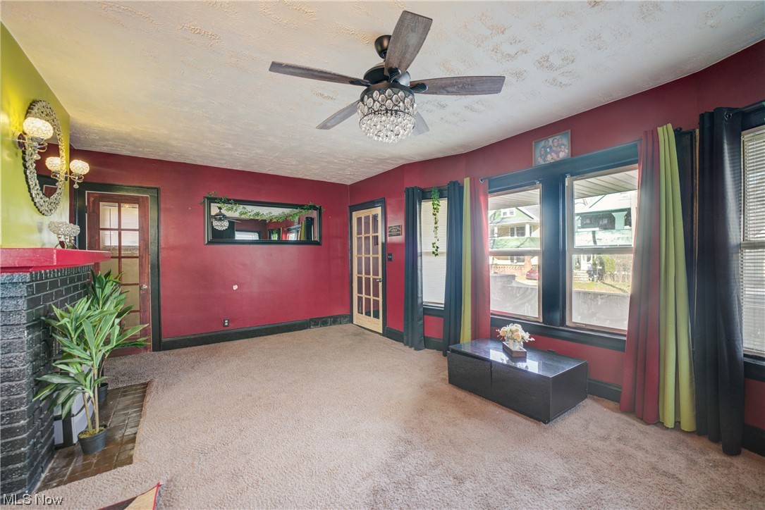14202 Glenside Road Cleveland, OH 44110 - Photo 26 of 41 Living room featuring a textured ceiling, ceiling fan, a fireplace, and carpet