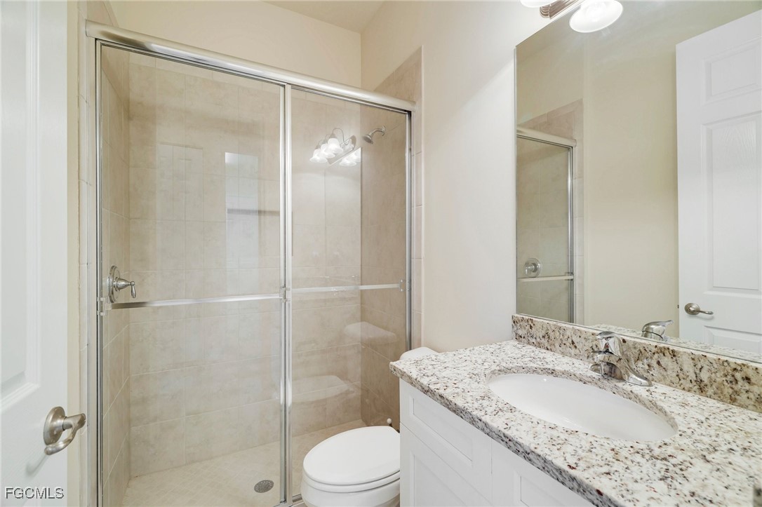 11643 Meadowrun Circle Fort Myers, FL 33913 - Photo 21 of 39 a bathroom with a granite countertop sink toilet mirror and shower