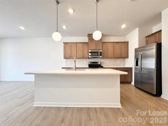 a kitchen with kitchen island a counter space a sink appliances and cabinets
