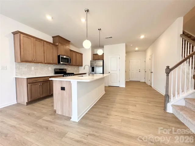 a large kitchen with stainless steel appliances kitchen island granite countertop a stove a sink a oven and a wooden cabinets