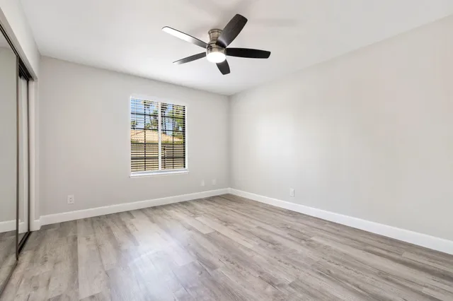 an empty room with wooden floor and ceiling fan