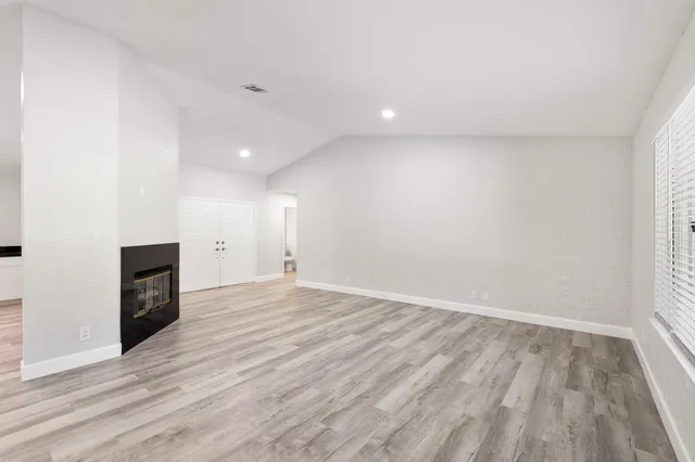 an empty room with wooden floor and fireplace