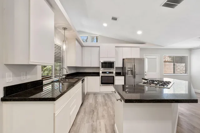a kitchen with granite countertop stove and cabinets