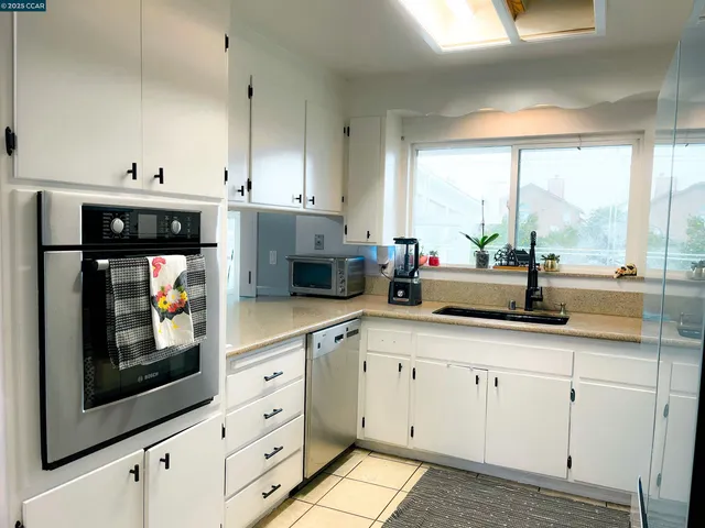 a kitchen with stainless steel appliances a sink a stove and white cabinets