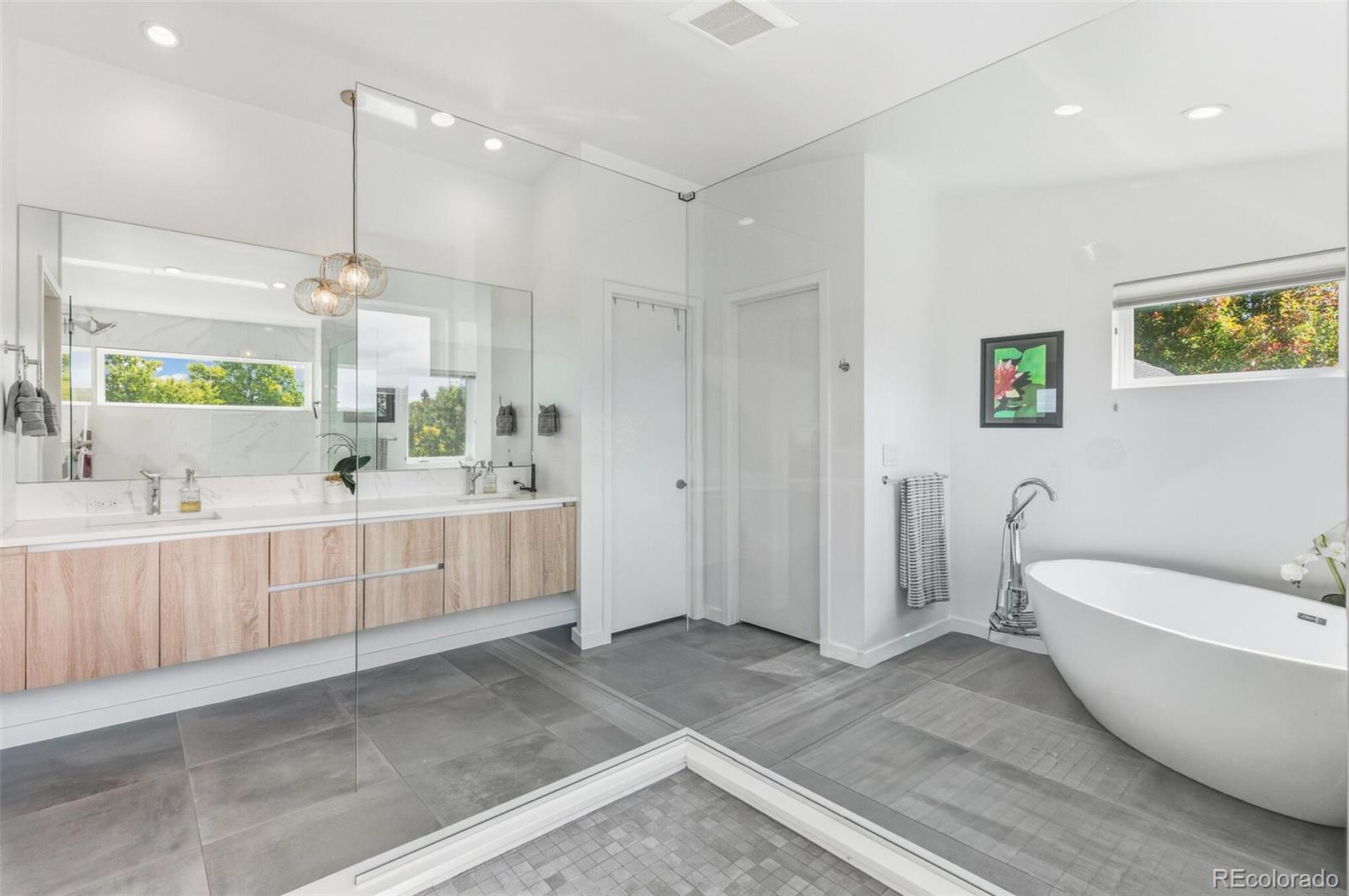 4077 Everett Street Wheat Ridge, CO 80033 - Photo 31 of 50 a bathroom with a white tub a vanity a sink and a window