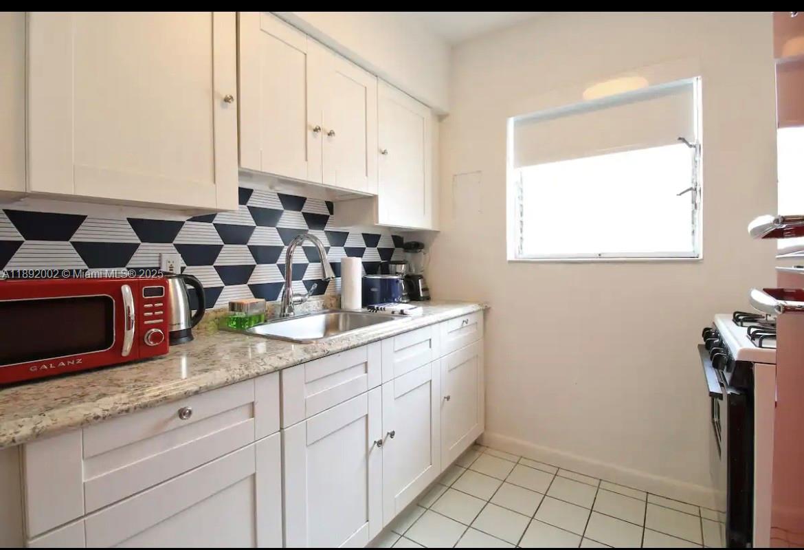 7721 Harding Avenue, Unit 9 Miami Beach, FL 33141 - Photo 9 of 10 a kitchen with stainless steel appliances granite countertop white cabinets and a window