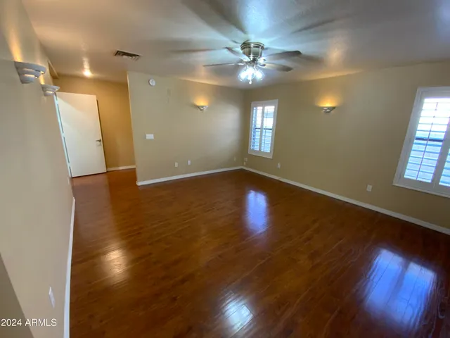 a view of an empty room with window and wooden floor