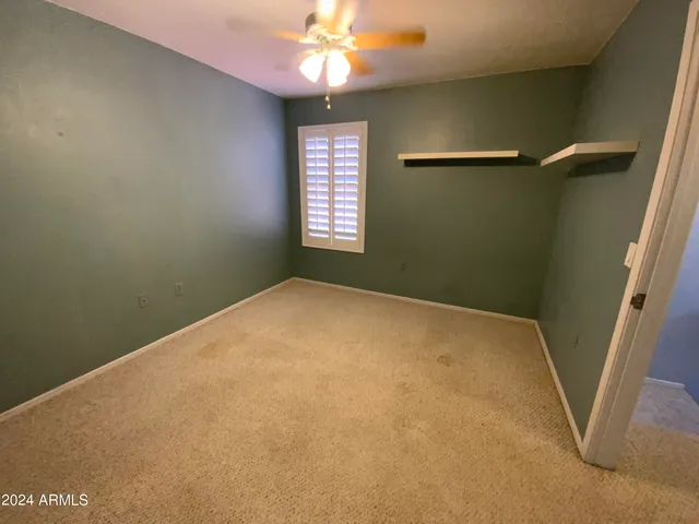 an empty room with windows and fan
