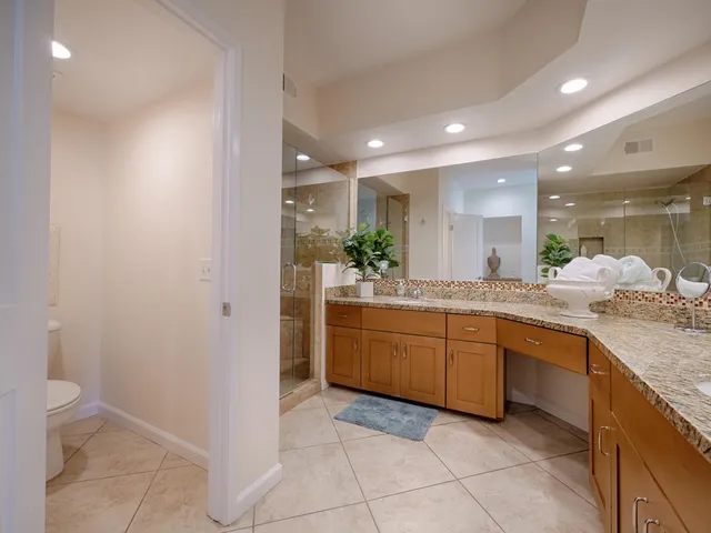 a large bathroom with a granite countertop sink a mirror and a toilet